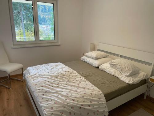 two beds in a bedroom with a chair and a window at Salzkammergut View in St. Wolfgang