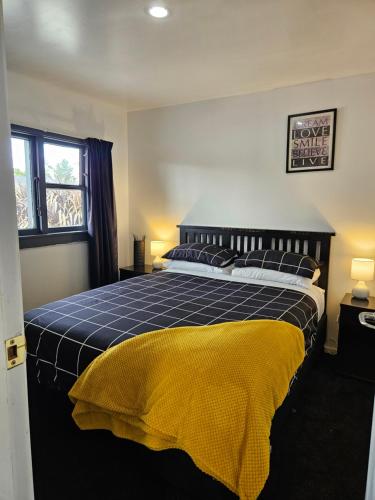a bedroom with a bed with a yellow blanket on it at Marg's on the Corner in Kumara