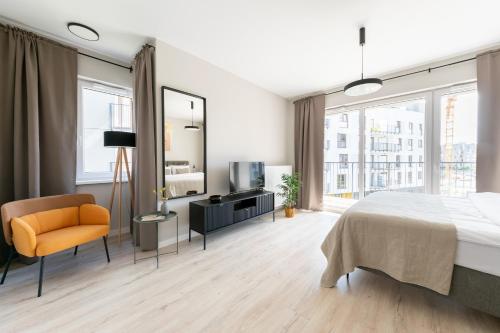 sypialnia z łóżkiem, telewizorem i krzesłem w obiekcie Platinum Apartments w Warszawie