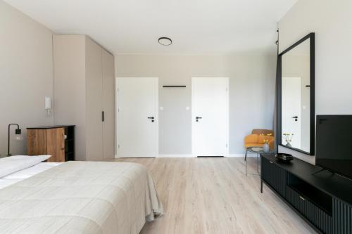 a white bedroom with a large bed and a television at Platinum Apartments in Warsaw