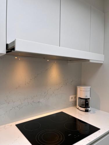 a kitchen with white cabinets and a coffee maker on a counter at Huyze Ter Vaete in Lo-Reninge