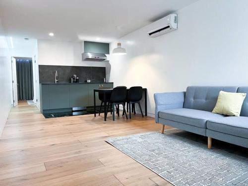 a living room with a blue couch and a kitchen at New Cozy Modern Minimalist Stay in Brooklyn at Rem-Casa in Brooklyn
