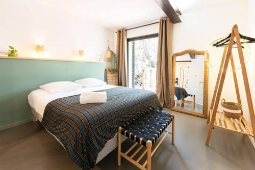 ein Schlafzimmer mit einem Bett, einem Spiegel und einem Stuhl in der Unterkunft La Coursive : belle maison de standing avec piscine in Montpellier