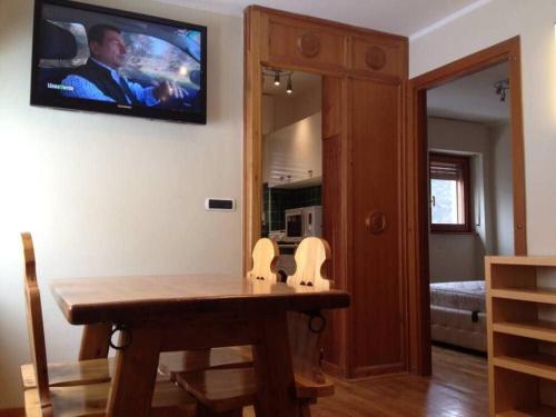 a room with a table and a television on the wall at Bilocale 5 posti letto Colle Sestriere in Sestriere
