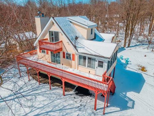 a house with a red deck in the snow at PoconoChalet-Hot Tub-Grill-Firepit-Games in Long Pond