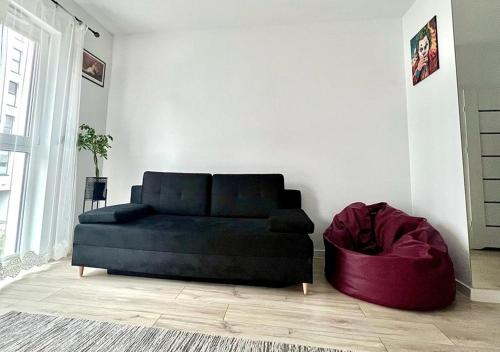 a black couch in a living room with a red ottoman at George Studio przy Stadionie Narodowym in Warsaw