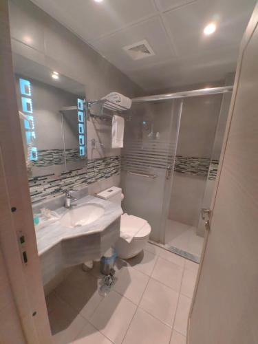 a bathroom with a toilet and a sink and a shower at فندق دان البلاتيني in Al Madinah