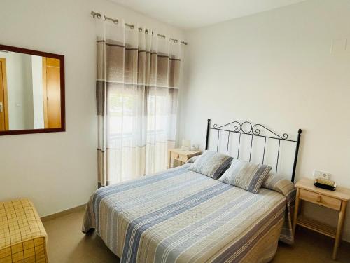a bedroom with a bed and a mirror and a window at Ático Premium Conil con 2 terrazas, parking, piscina, Aire Ac y WIFI -SOLO FAMILIAS Y PAREJAS- in Conil de la Frontera