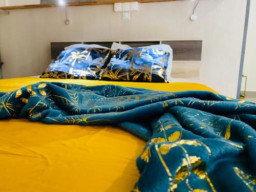 2 Betten mit blauen und gelben Decken darauf in der Unterkunft Appartement Cosy design in Schœlcher