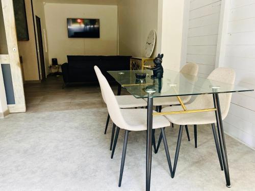 a dining room with a glass table and chairs at Appartement Cosy design in Schœlcher