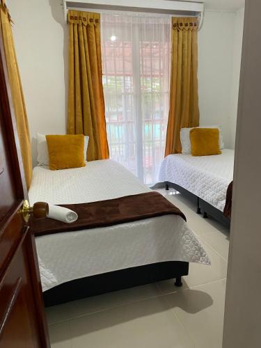 a bedroom with two beds and a window at Casa Turistica JM in Armenia