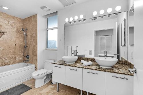 a bathroom with two sinks and a tub and a toilet at Duplex 2BR in Miami