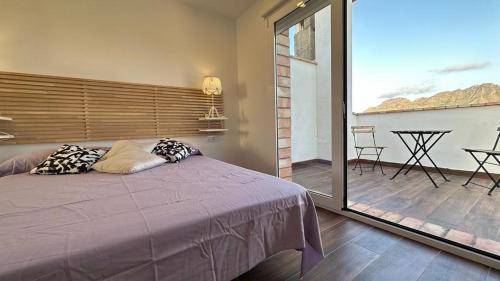 a bedroom with a purple bed and a balcony at La bocana del Portús in Cartagena