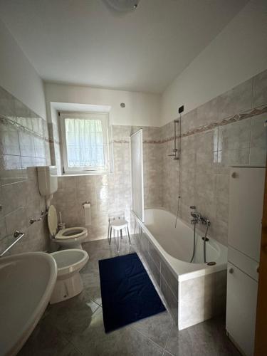 ein Badezimmer mit einer Badewanne, einem WC und einer Badewanne in der Unterkunft CA' EDDA APPARTAMENTO ANNA in Brentonico