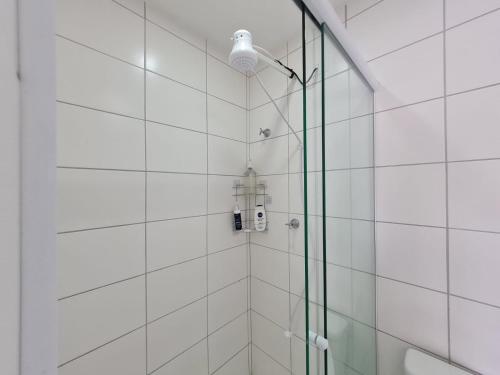 una ducha con una luz en una pared de azulejos blancos en Studio próximo Avenida Paulista, en São Paulo
