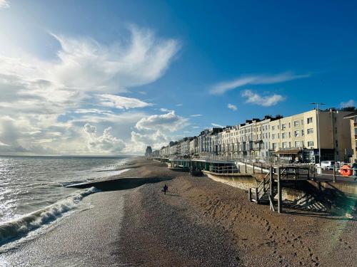 a beach with a row of buildings and the ocean at Newly refurbished two bedrooms flat in St. Leonards