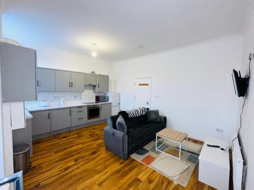 a living room with a couch and a kitchen at Newly refurbished two bedrooms flat in St. Leonards