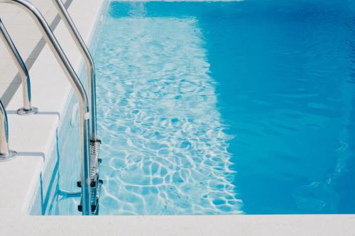 a swimming pool with blue water and metal rails at AMI in Solin