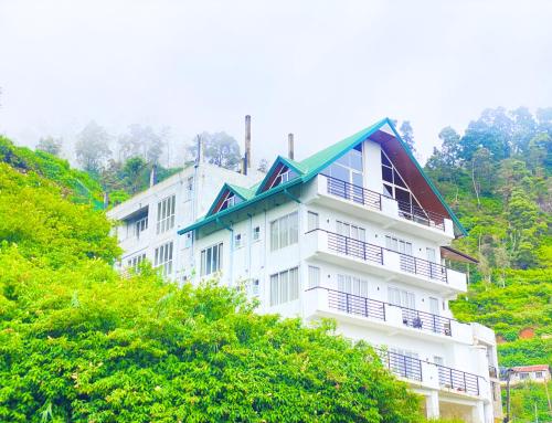 un bâtiment blanc avec un toit vert sur une colline dans l'établissement Queens Mount Glen Heights, à Nuwara Eliya