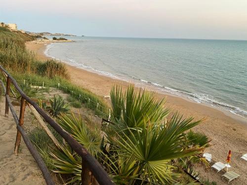 a beach with chairs and a fence and the ocean at TorrediGaffe Home, una casa nella piazzetta del borgo a due passi dal mare in Torre di Gaffe