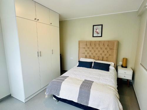 1 dormitorio con 1 cama grande con almohadas azules en Las Viñas - Departamentos Privados, en Ica