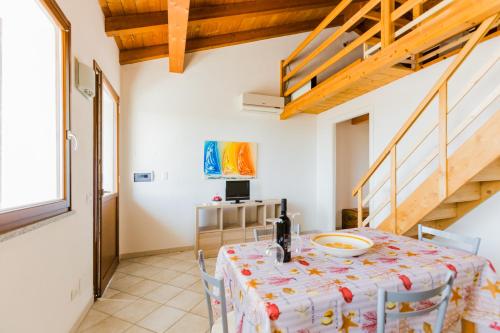 a dining room with a table and a staircase at Residence Fior di Sulcis in Calasetta