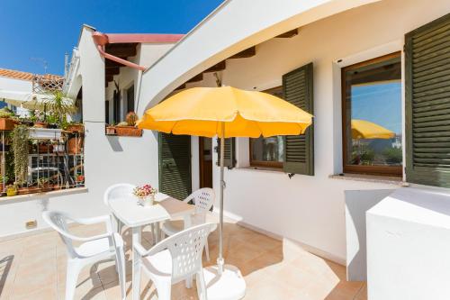 a table with a yellow umbrella on a balcony at Residence Fior di Sulcis in Calasetta