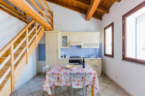 a kitchen with a table in a room with wooden ceilings at Residence Fior di Sulcis in Calasetta