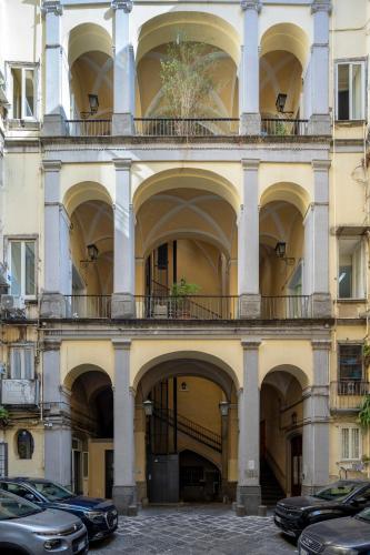 a large building with arches and cars parked in front at Napolit'amo Hotel Principe in Naples