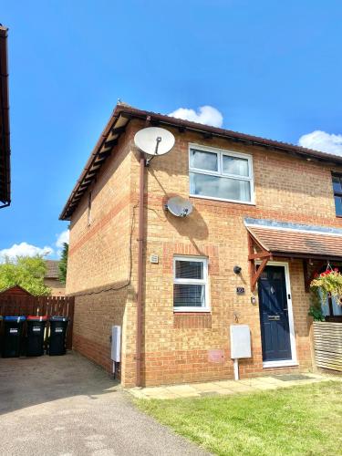 a brick house with a satellite on the side of it at Central MK Home, Garden and Free Private Driveway Parking! 4 Beds Fully Equipped Train station 5 Mins in Milton Keynes