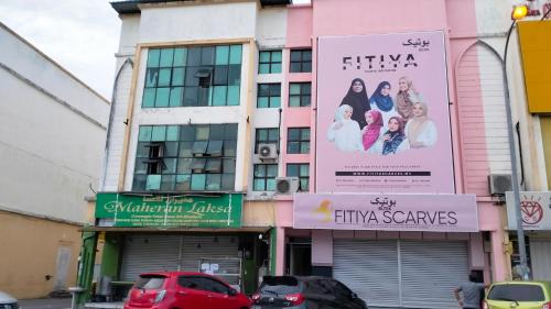 a pink building with cars parked in front of it at Hostel Dena moon inn 3 in Kota Bharu