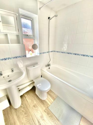 a white bathroom with a toilet and a sink at Central MK Home, Garden and Free Private Driveway Parking! 4 Beds Fully Equipped Train station 5 Mins in Milton Keynes