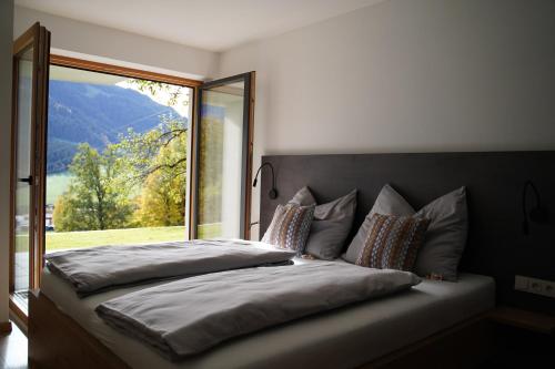 - une chambre avec un lit et une grande fenêtre dans l'établissement Alpenchalet zurHinterochsenweide SKI IN & SKI OUT, à Brixen im Thale