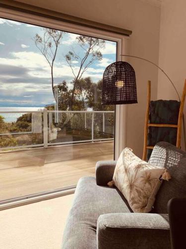a living room with a couch and a large window at Beachfront House - Hot Tub, Ocean Views, Private Beach Pathway in White Beach