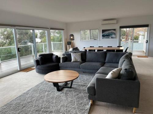 a living room with a blue couch and a table at Beachfront House - Hot Tub, Ocean Views, Private Beach Pathway in White Beach