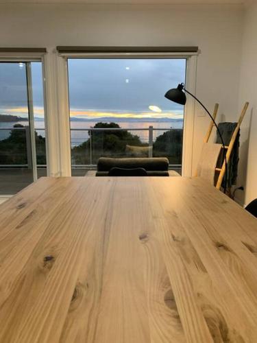 a wooden table in a room with a large window at Beachfront House - Hot Tub, Ocean Views, Private Beach Pathway in White Beach