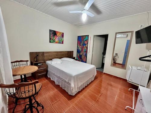 Recanto Toca das Plantas de Ilhabela I في إلهابيلا: غرفة نوم بسرير وطاولة ومروحة سقف