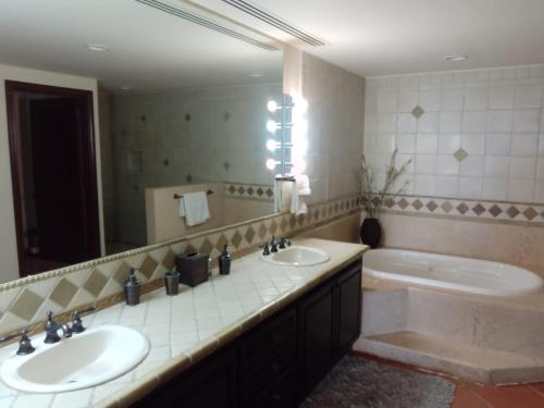a bathroom with two sinks and a tub and a mirror at delfines 204 in Cabo San Lucas