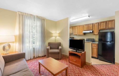 a living room with a couch and a tv and a kitchen at Extended Stay America Suites - Chantilly - Dulles in Chantilly