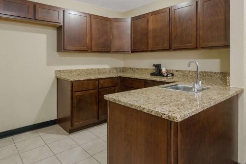 a kitchen with a sink and wooden cabinets at Quality Inn & Suites Roanoke - Fort Worth North in Roanoke
