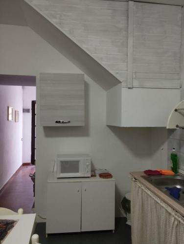 a kitchen with white cabinets and a microwave at casa vacanze Cettina home 2 mt 50 dal mare in Terra Mala