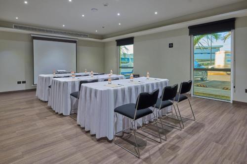 a conference room with tables and chairs and a screen at City Express by Marriott Guaymas in Guaymas