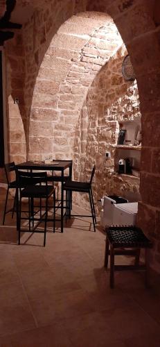 a room with two tables and chairs and a stone wall at Dimora Cleó in Putignano