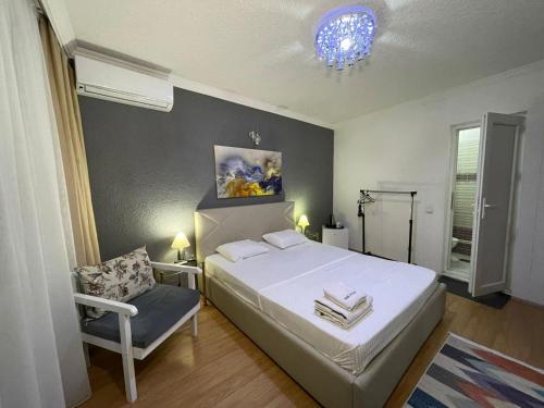 a bedroom with a white bed and a chair at Deni house in Prizren