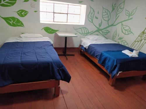 a bedroom with two beds and a window and a table at DEJAVU in Chachapoyas