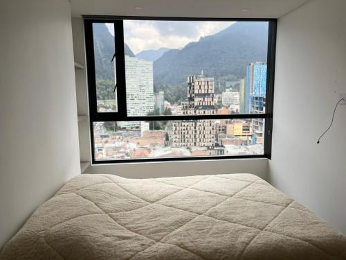 a bed in a room with a large window at Apartamentos Centro Bogotá piso 16 y o piso 23 -Vista Monserrate in Bogotá