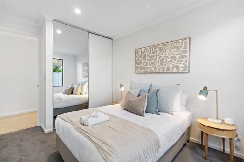 a white bedroom with a large bed and a mirror at Driftwood Port Noarlunga South in Port Noarlunga South
