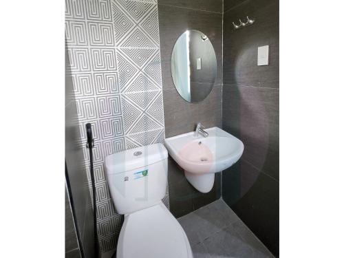 a bathroom with a toilet and a sink and a mirror at RiCres Hometel Double Bed R124 in Samal