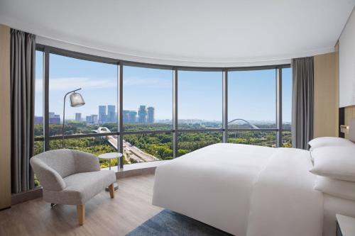 Cette chambre comprend un lit blanc et une chaise. dans l'établissement Courtyard by Marriott Beijing Changping, à Pékin