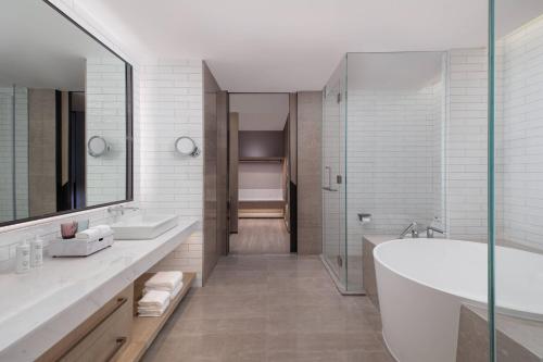 ein Badezimmer mit zwei Waschbecken, einer Badewanne und einer Dusche in der Unterkunft Courtyard by Marriott Beijing Changping in Peking